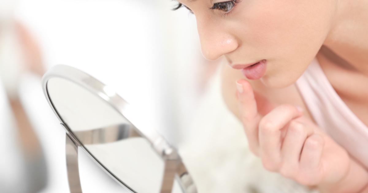 someone looking at their lips in the mirror